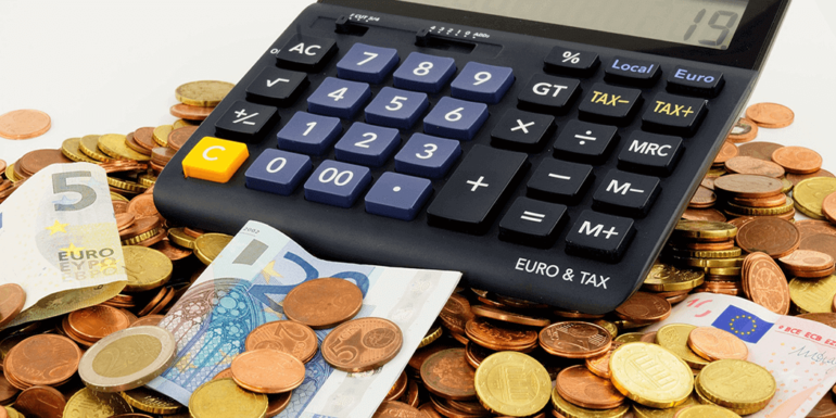 A calculator on top of a pile of money.